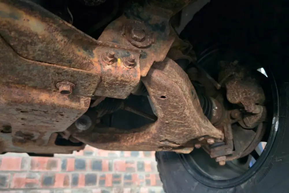 Front control arm & hub before treatment — heavy surface corrosion across the steel
