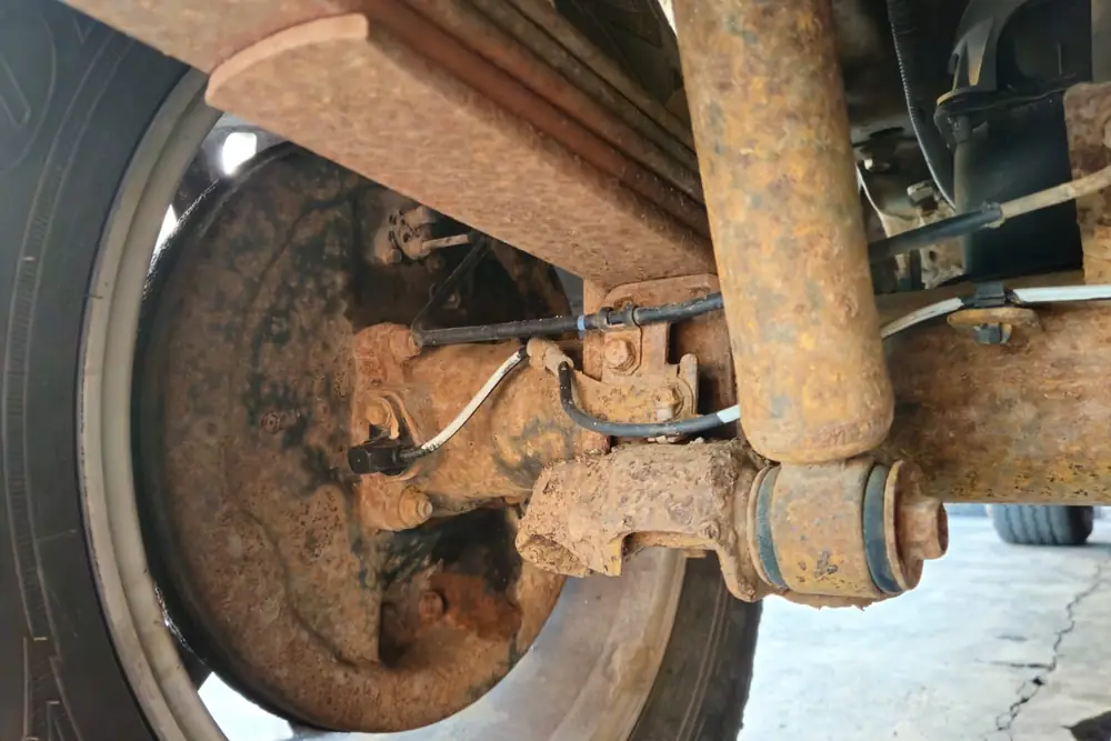 Rear axle & fuel tank before treatment — heavy surface corrosion across the steel