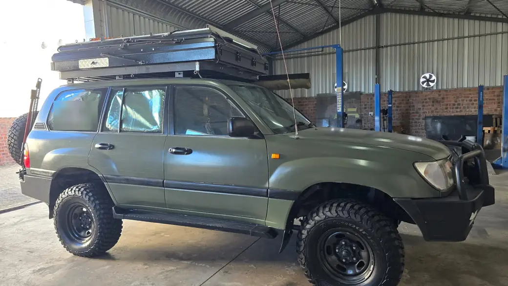 Olive green Toyota Land Cruiser 100 Series with a roof tent in the Anti-Rust workshop