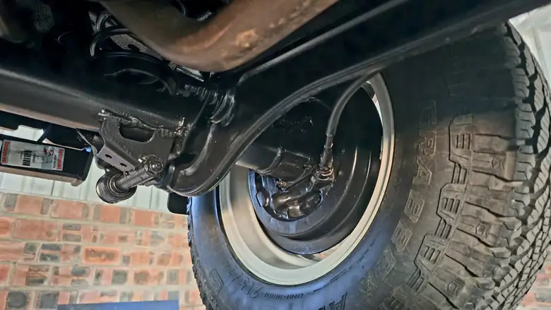 Rear axle, drum backing plate and trailing arm