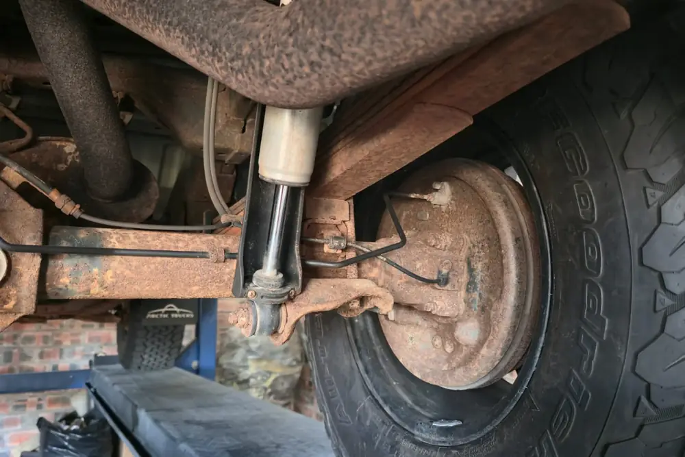 Leaf springs & brake drum before treatment — heavy surface corrosion across the steel